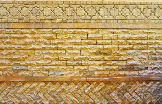 Old weathered wall with varied brick patterns and simple mosaic border at the top abstract monochromatic background texture