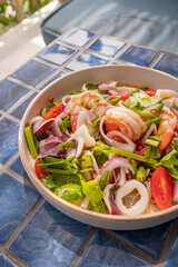 Close up, Spicy seafood salad in bowl on blue tiled surface, Thai dish