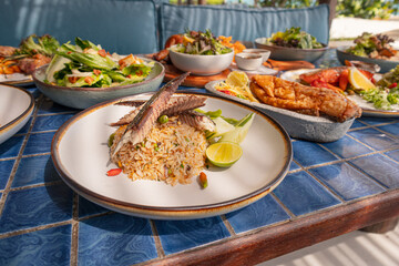 Fried rice with mackerel and include chili, lime and cucumber in plate on blue tiled surface