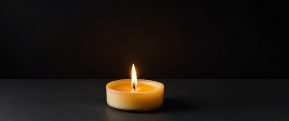 A warm candle glowing softly on a black background, ideal for relaxation and ambiance