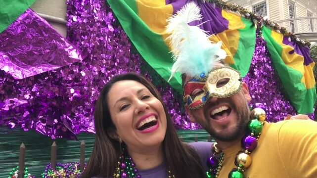 Happy latin tourists friends heterosexual couple celebrating their Honeymoon in Mardi Gras in New Orleans dressing necklace and masks. Mardi Gras is the most important celebration for the city.