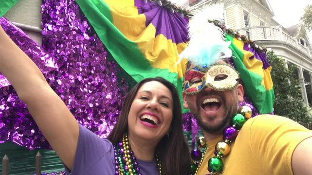 Happy latin tourists friends heterosexual couple celebrating their Honeymoon in Mardi Gras in New Orleans dressing necklace and masks. Mardi Gras is the most important celebration for the city.