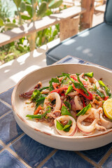 Close up, Spicy fried squid with shrimp paste in plate on blue tiled surface, Thai dish