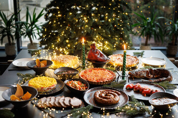 Festive table setting with Christmas decorations and burning candles in the dining room, cozy romantic Christmas in the evening atmosphere