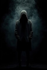 Mysterious cloaked figure in black hoodie illuminated by shadows, dark environment, silhouette in casual wear, Halloween theme, sinister presence lurking in darkness