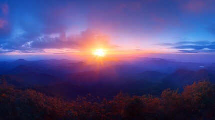 Obraz premium Vibrant sunrise over majestic mountain range, showcasing colorful sky and sun rays.