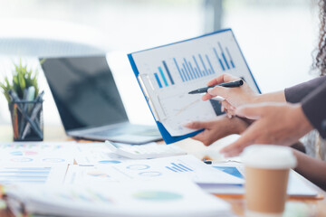 Analyzing Data: Close-up of hands reviewing financial charts and graphs, showcasing a collaborative and focused approach to business strategy and growth.  