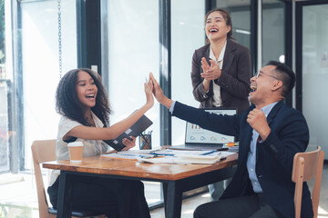 High Five Success: Celebrating a deal closed. Two happy business colleagues give a high five while a manager applauds their success in a modern office setting.  