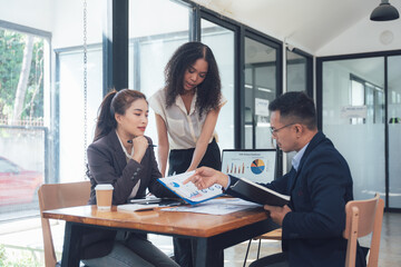 Strategic Business Meeting:  A focused team of Asian business professionals collaborates around a table, reviewing charts and financial documents.