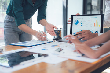 Strategic Collaboration: Business team analyzing data on laptop and documents, close-up view of hands and charts. A scene of focused teamwork and insightful discussion.