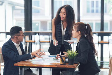Business Meeting Brainstorm: A diverse team of professionals engaged in a dynamic discussion over a table, showcasing collaboration and shared ideas in a modern office setting.  