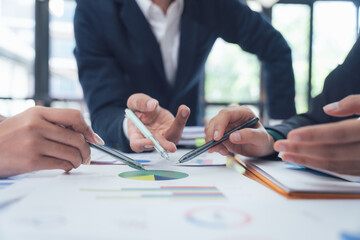 Strategic Collaboration: Hands actively engaged with financial charts, showcasing a focused business meeting and collaborative problem-solving.  A candid depiction of teamwork and strategic planning.