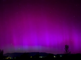 Majestic magenta and purple northern lights illuminating the night sky in La Cerdanya, Pyrenees, Spain. May 2024