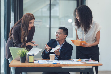 Collaborative Brainstorming: A diverse team of colleagues engage in lively discussion around a desk, showcasing the energy and creativity of a modern workplace.
