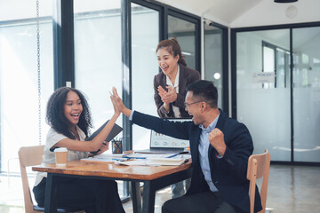 High Five for Success: Three diverse colleagues celebrate a win in a modern office setting. The image captures the energy and excitement of teamwork.