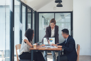 Strategic Business Meeting: Diverse team collaboration around a table, analyzing data on a laptop screen. A female leader guides the discussion, fostering a productive and collaborative atmosphere. 