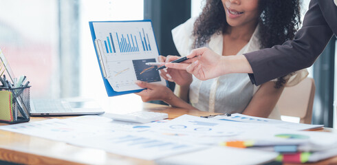 Businesswomen Collaborating: A close-up shot of two businesswomen collaborating over a business...