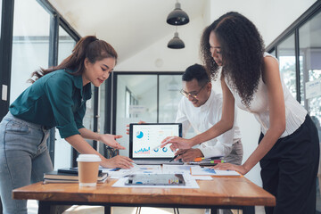 Collaborative Brainstorming: A diverse team of professionals huddle around a laptop, analyzing data and strategizing their next move in a modern office setting, showcasing teamwork, collaboration.