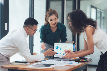 Teamwork Makes the Dream Work: Diverse business colleagues collaborate on a project, reviewing data and charts on a laptop and papers.