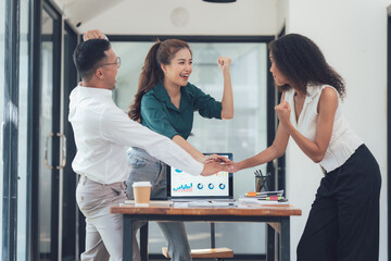 Office Celebration:  A diverse team of professionals celebrates a shared success, their hands clasped together around a laptop displaying a positive graph.