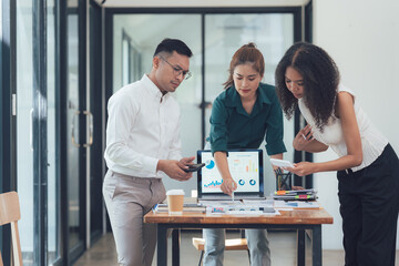 Collaborative Business Analysis: A diverse team of professionals collaborates on a project, reviewing data and documents in a modern, bright office setting.