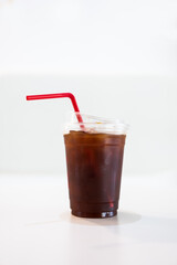 Iced americano coffee in plastic cup with red straw on table
