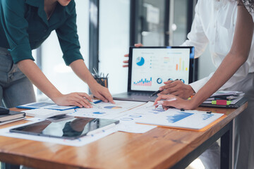 Teamwork Makes the Dream Work: A close-up shot of a collaborative team reviewing data on a laptop and papers, showcasing their dedication and focus on achieving shared objectives.  