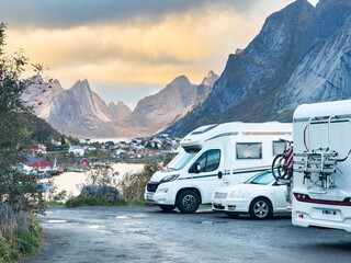 Parked camper vans and car enjoying scenic view of reinebringen mountain and fishing village of reine in lofoten islands, norway