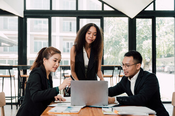 Collaborative Business Meeting: Diverse Team Brainstorming. A diverse team of business professionals collaborates around a laptop, engaging in a productive meeting.