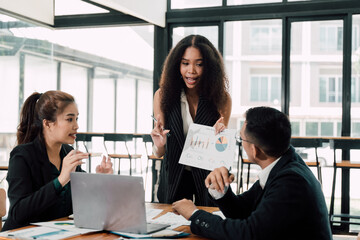 Business Meeting -  A diverse team of professionals engages in a lively discussion, analyzing data and charts around a table in a modern office setting.