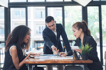 Focused Business Team Collaboration: A diverse team of professionals engages in serious discussion over documents, showcasing focused collaboration and strategic planning in a modern office setting.
