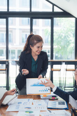 Confident Presentation: A mature businesswoman confidently presents data during a meeting, showcasing her leadership and expertise.