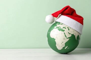 Festive Globe with Santa Hat Surrounded by Lush Greenery For Christmas