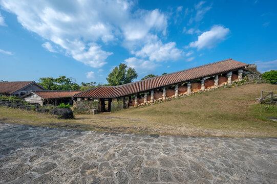 The Yomitanzan-yaki cooperative "climbing" kiln, in Yachimun no Sato in Okinawa, is topped by a traditional red-tile roof. The kiln is at the center of the village and is near several pottery studios.