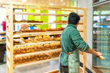 Man placing baked bread to shop using a peel