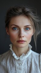 Portrait of a woman with striking blue eyes, wearing a vintage white lace blouse, against a dark background.