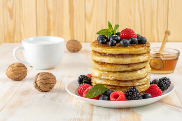 Delicious pancakes with fresh berries on white wooden table. Food concept.