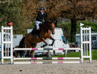 Beautiful young rider on her mare with her protective vest during a show jumping competition