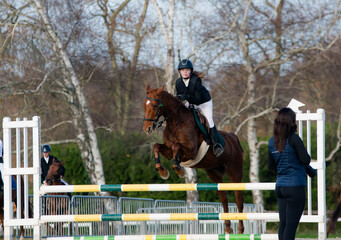 Beautiful young rider on her mare with her protective vest during a show jumping competition