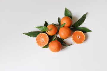 Decorative fresh fruit composition. Whole and sliced orange tangerines, citrus fruit and leaves isolated on white table background. Food pattern. Empty space. Flat lay, top view. Mediterranean design.
