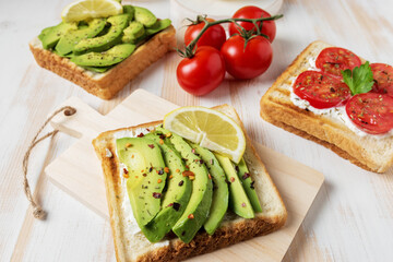 Sliced avocado on toast bread with spices on white wooden background. Food concept.