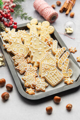 Christmas cookies decorated with icing on baking tray with festive decorations