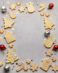 Christmas gingerbread cookies and ornaments creating festive frame on grey background