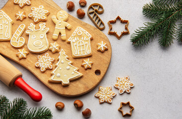Christmas cookies decorated with icing on wooden board with fir branches and hazelnuts
