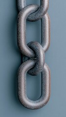 Obraz premium A close-up of a metallic chain link against a solid background, showcasing its texture and structure.