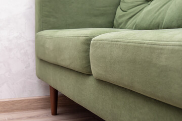 Green sofa or armchair with wooden legs. Padded seat