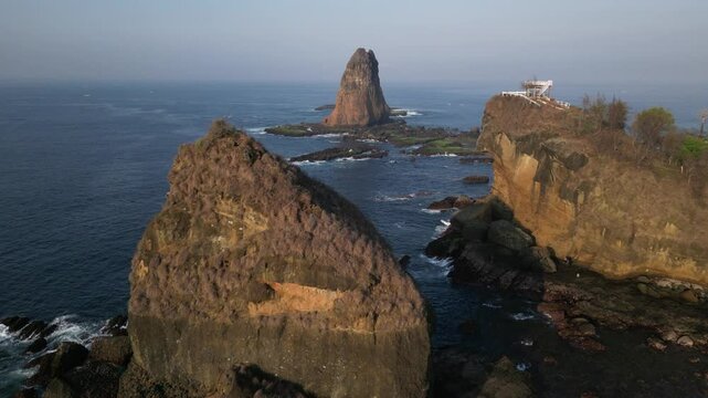 Drone aerial view of papuma beach at sunrise with waves and rocks