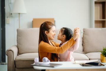 A caring mother and young daughter share a bonding moment doing homework at home.