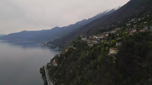 Ronco sopra Ascona, Ticino, Switzerland, by lake Maggiore in Switzerland from above, featuring colorful buildings, lush greenery, and a serene lake surrounded by majestic alps mountains drone orbiting