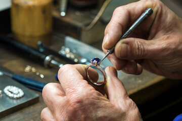 Manos de un artesano joyero trabajando con un anillo con un piedra azul. Generado con IA